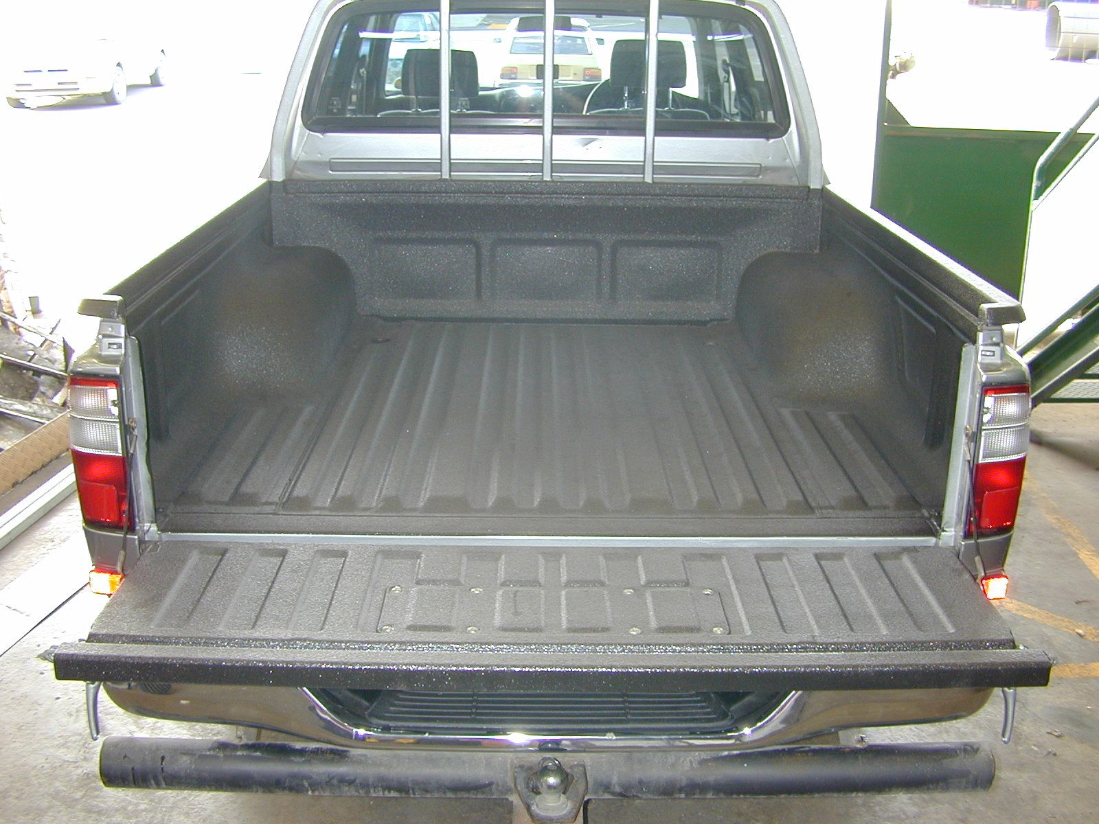 Pickup truck bed with sprayed polyurea coating rather than bed paint